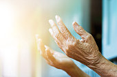 Elderly woman hands praying with peace of mind and faithfully.