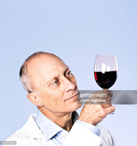 serious wine-tasting scientist checks clarity and colour of red wine - critic stockfoto's en -beelden