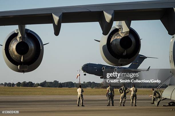 Air Force maintainers from the 437th Aircraft Maintenance Squadron watch as a C-17 Globemaster III lands on the flightline at Fort Campbell,...