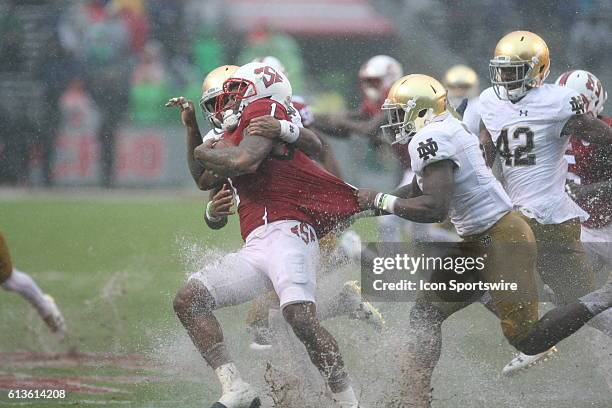 State Wolfpack fullback Jaylen Samuels runs the ball and is tackled by Notre Dame Fighting Irish cornerback Julian Love and Dexter Williams during...