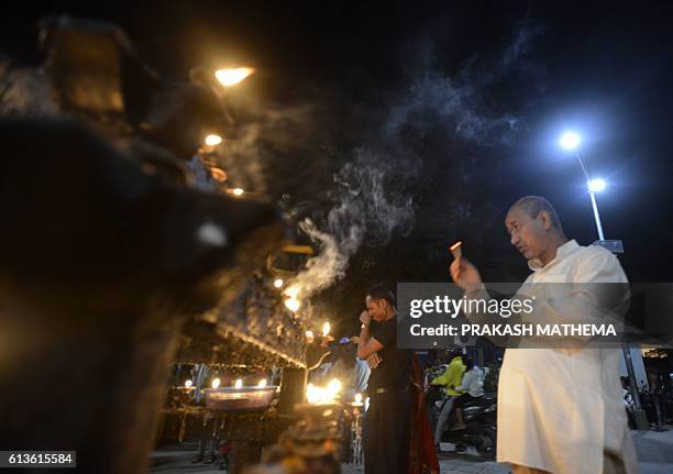 Nepali Hindu devotee prays with lit incense sticks in front the Hindu God Kaal Bhairav in Durbar Square during the Hindu Festival Dashain in...