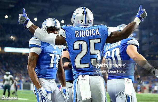 Theo Riddick of the Detroit Lions celebrates his second touchdown of the game with teammates Cornelius Lucas and Graham Glasgow against the...