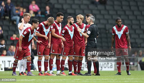 Referee Sebastian Stockbridge talks to Port Vale players as they line up to defend a free kick during the Sky Bet League One match between Milton...