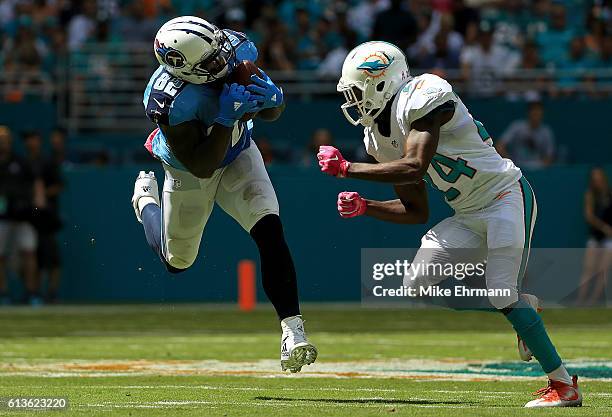 Delanie Walker of the Tennessee Titans makes a catch over Isa Abdul-Quddus of the Miami Dolphins during a game on October 9, 2016 in Miami Gardens,...