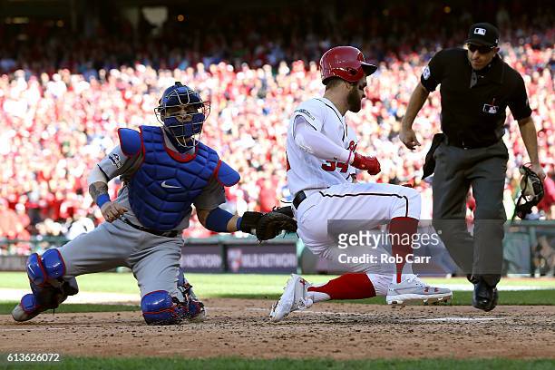 Bryce Harper of the Washington Nationals is tagged out at home plate by Yasmani Grandal of the Los Angeles Dodgers for the third out of the fifth...