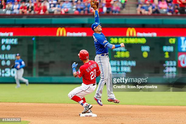 Texas Rangers center fielder Ian Desmond slides into second base as Toronto Blue Jays shortstop Troy Tulowitzki leaps for the baseball during the...