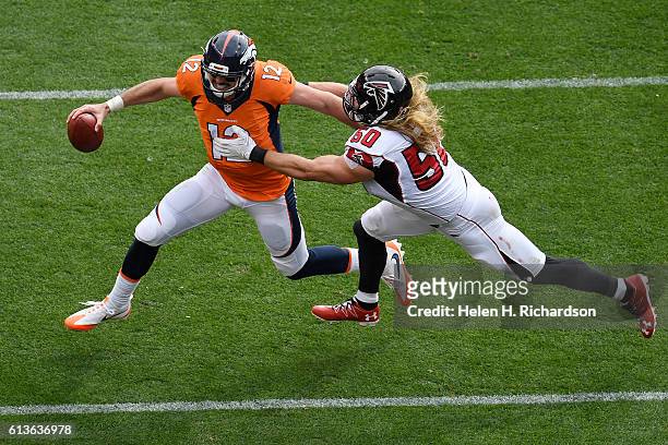 Paxton Lynch of the Denver Broncos scrambles as A.J. Hawk of the Atlanta Falcons grabs him during the first quarter. The Denver Broncos hosted the...