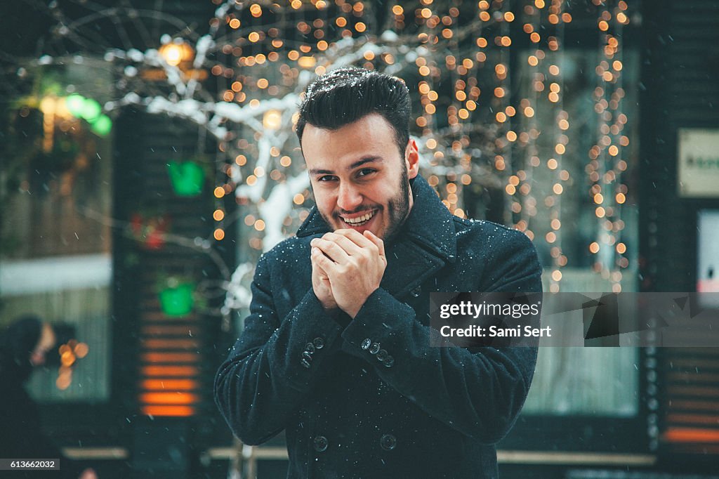 Happy Young man blowing on hands in winter