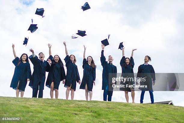 a group of graduates tossing their hats in celebration. - secondary school certificate stock pictures, royalty-free photos & images