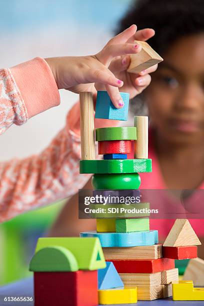 toddler builds tall tower with wooden blocks - peuterschool gebouw stockfoto's en -beelden