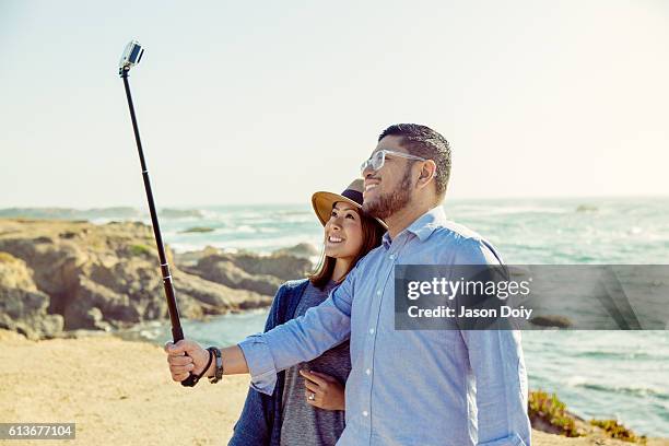 glückliches paar, das ein foto mit einem selfie stick macht - selfiestick stock-fotos und bilder