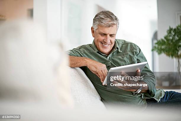 browsing at leisure - man middelbare leeftijd woonkamer stockfoto's en -beelden