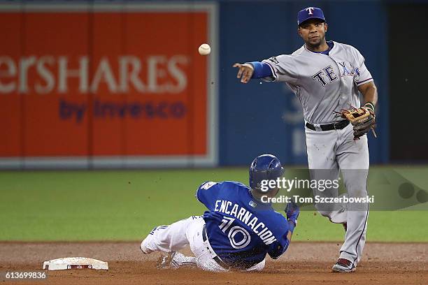 Elvis Andrus of the Texas Rangers turns a double play over Edwin Encarnacion of the Toronto Blue Jays for the final two outs of the fifth inning...