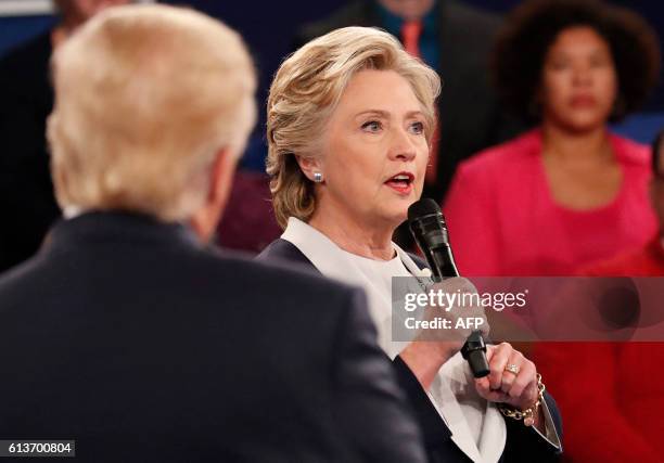 Democratic nominee Hillary Clinton speaks as Republican nominee Donald Trump looks on during the second presidential debate at Washington University...