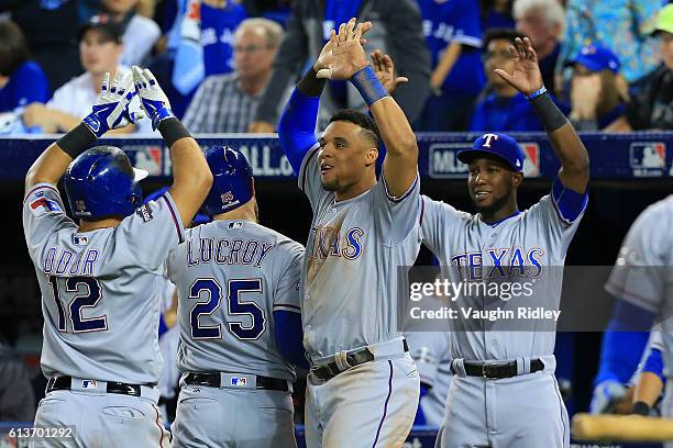 Jonathan Lucroy and Rougned Odor of the Texas Rangers celebrate with teammates after scoring on a two run double hit by Mitch Moreland in the sixth...