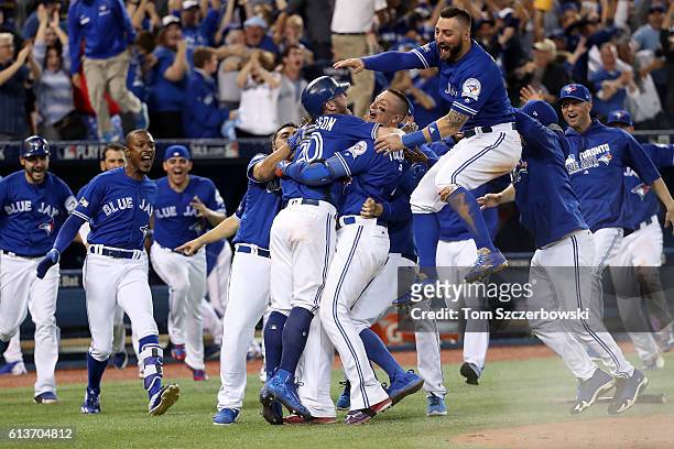 Josh Donaldson of the Toronto Blue Jays is swarmed by his teammates after the Toronto Blue Jays defeated the Texas Rangers 7-6 in ten innings for...