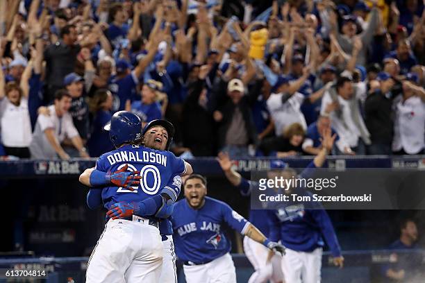 Josh Donaldson of the Toronto Blue Jays celebrates with teammate Troy Tulowitzki after the Toronto Blue Jays defeated the Texas Rangers 7-6 in ten...