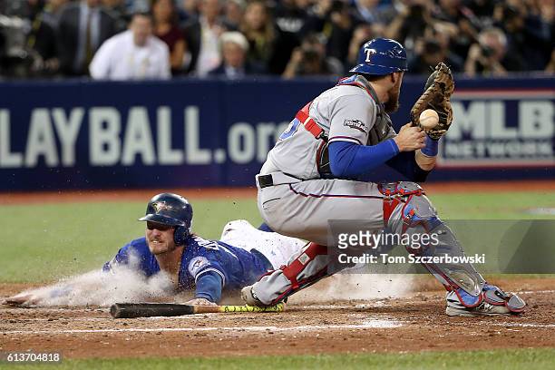 Josh Donaldson of the Toronto Blue Jays slides safely into home plate past Jonathan Lucroy of the Texas Rangers in the tenth inning for the Toronto...