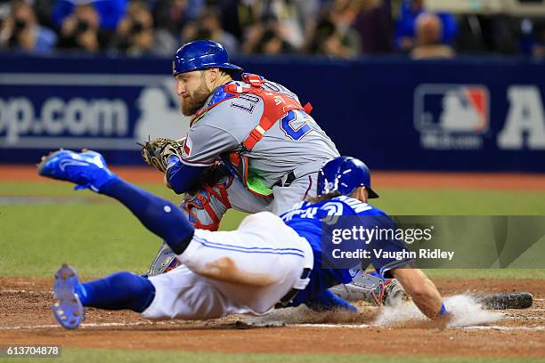 Josh Donaldson of the Toronto Blue Jays slides safely into home plate past Jonathan Lucroy of the Texas Rangers in the tenth inning for the Toronto...