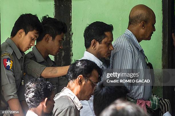 Defendants Hla Myint Oo and Khine Soe are escorted by police after their court trial in Shwe Pyi Thar township in the outskirts of Yangon on October...