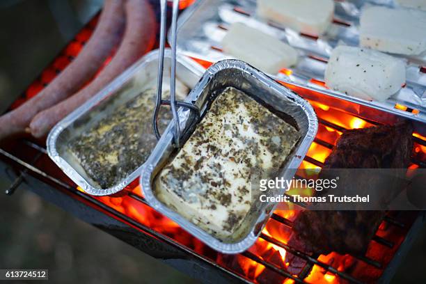 Schmorsdorf, Germany Grilled cheese is prepared in an aluminum dish on a grill next to bratwurst and a steak on October 01, 2016 in Schmorsdorf,...
