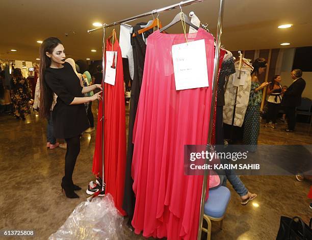 Emirati model Rafeea Al-Hajsi looks at dresses by Lebanese designer Aiisha Ramadan prior to the walking down the catwalk in Ramadan's show at the...