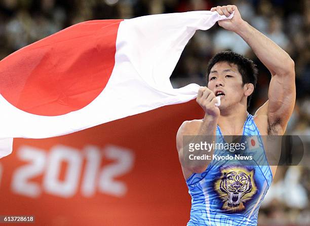 Britain - Japan's Tatsuhiro Yonemitsu waves the Japanese national flag in celebration of his gold medal victory in the men's 66 kilogram freestyle...