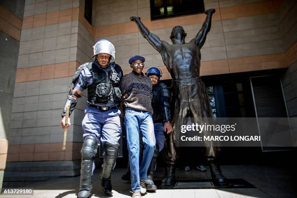 Student is detained by a South African ant riot policeman after he entered a building of the Witwatersrand University in Johannesburg on October 10,...