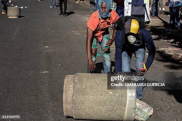 People roll down a concrete outside bin during clashes between students from the University of Witwatersrand and South African police in downtown...