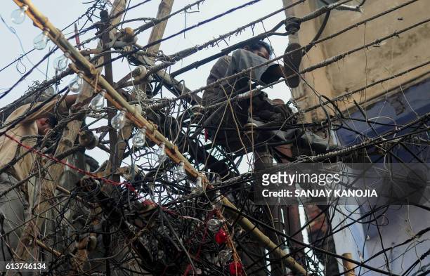 An Indian electrician sits on a tangle of wires as he adjusts the cables ahead of the Hindu Dussehra festival in Allahabad on October 10, 2016.