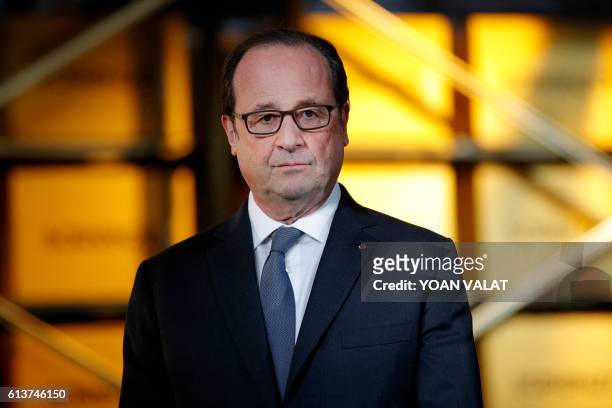 French President Francois Hollande stands as he visits the logistics center of French online shoe retailer Sarenza in Reau, near Paris, on October...