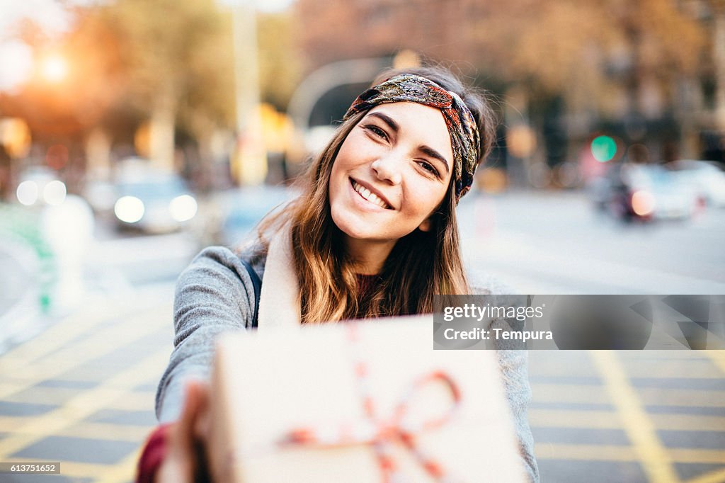 Young beautiful woman handing a present.