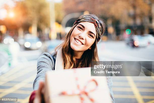 young beautiful woman handing a present. - oferecer imagens e fotografias de stock