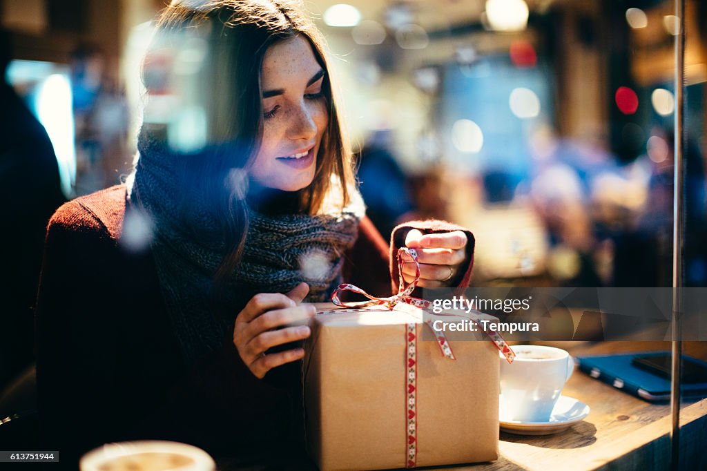 Young beautiful woman opening a present.
