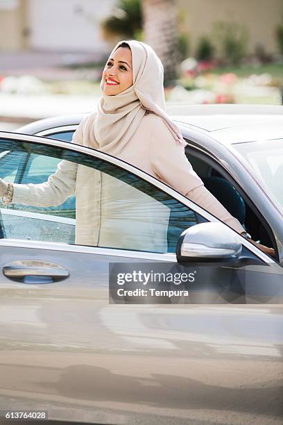 middle easter woman entering a luxury car in dubai - arab woman driving stockfoto's en -beelden