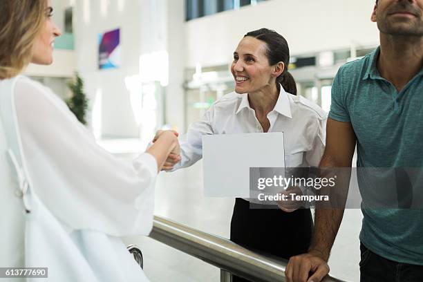 driver greeting business woman with a sign on arrival terminal. - airport signage stock pictures, royalty-free photos & images