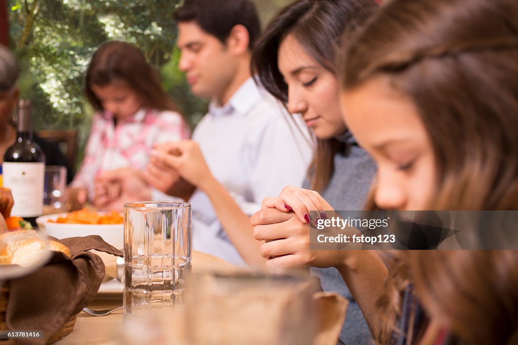 Family praying before Thanksgiving dinner at grandmother's home.