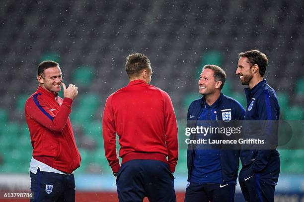 Wayne Rooney of England smiles as he speaks with Interim Manager Gareth Southgate, first-team coach Steve Holland and Jamie Vardy during a tour of...