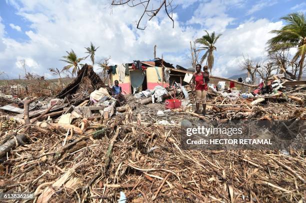 People stand next to their destroyed house in Les Cayes, Haiti on October 10 following the passage of Hurricane Matthew. Haiti faces a humanitarian...