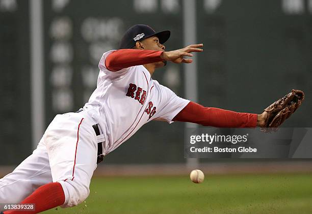 Wind blown pop up fly ball hit by Cleveland Indians designated hitter Carlos Santana , not pictured, eludes a diving Boston Red Sox shortstop Xander...