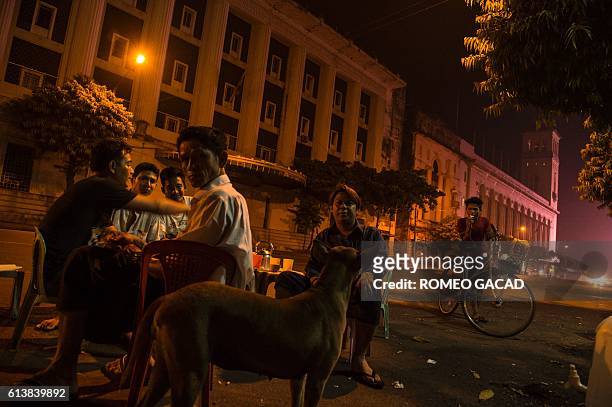 In this photograph taken on March 12 a stray dog stands next to customers at a roadside tea shop in Yangon. More than 100,000 stray dogs roam the...