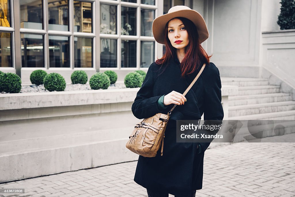 Trendy woman wearing winter coat and hat on the street