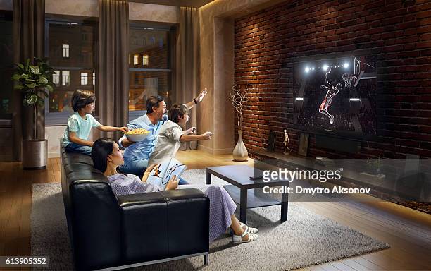 familia con niños animando y viendo el partido de baloncesto en la televisión - familia viendo television fotografías e imágenes de stock