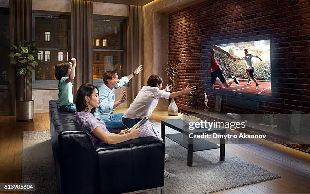 family with children cheering and watching relay race on tv - family relay stock pictures, royalty-free photos & images