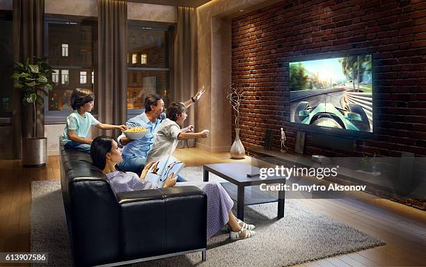 family with children watching sports car race on tv - tv family stockfoto's en -beelden