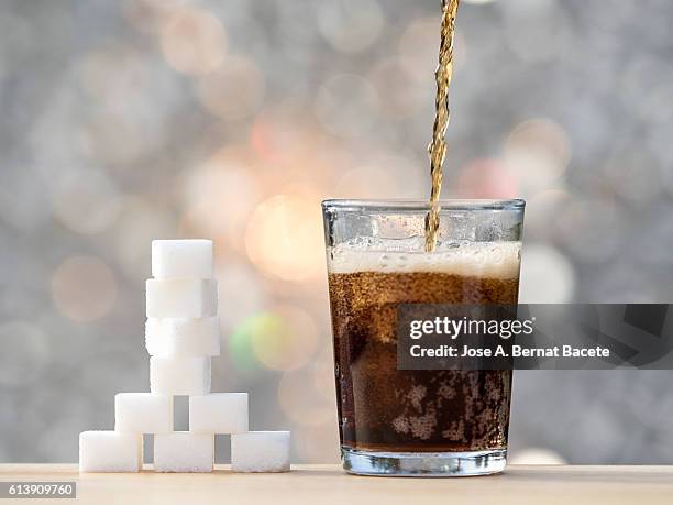 filling a glass with cola and its equivalent in sugar cubes - altas luces fotografías e imágenes de stock