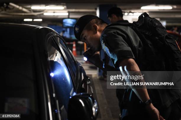 Policeman from the Crime Supression Division unit searches a car in the parking lot of a shopping mall in Bangkok on October 11, 2016. Thailand's...