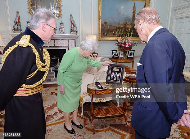 Queen Elizabeth II with the Duke of Edinburgh talk with Lieutenant Geneneral Richard Nugee, as he presents them both with long service and good...