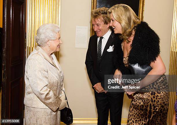 Queen Elizabeth II greets Sir Rod Stewart and wife Penny Lancaster after he was awarded a knighthood in recognition of his services to music and...