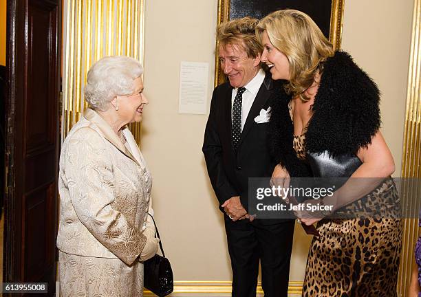 Queen Elizabeth II greets Sir Rod Stewart and wife Penny Lancaster after he was awarded a knighthood in recognition of his services to music and...